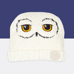 Harry Potter™ Hedwig Winter Hat flat lay – white knit beanie with embroidered owl eyes and beak.