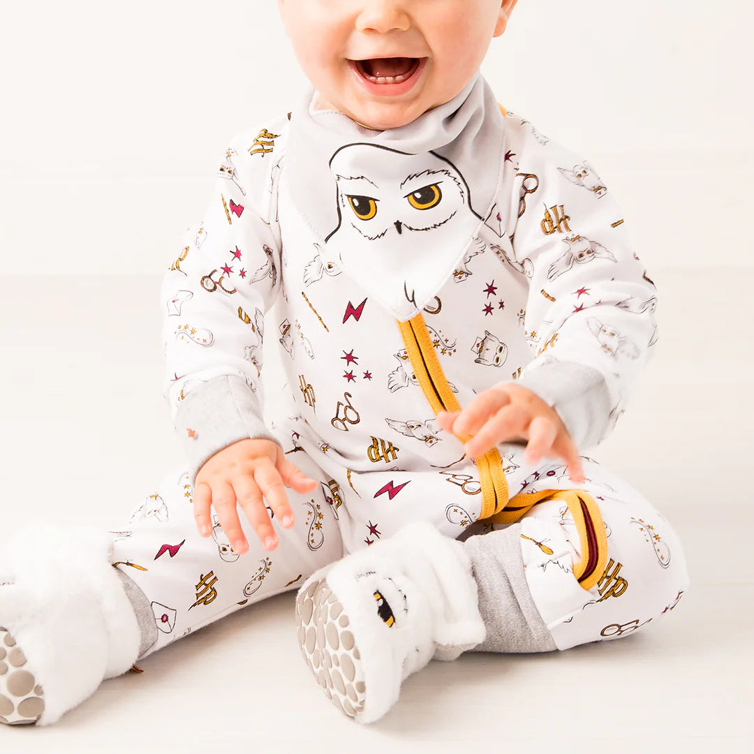 Smiling baby in Harry Potter™ Hedwig romper and matching owl booties.