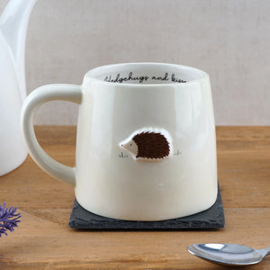 Stoneware mug with embossed hedgehog design on wooden table.