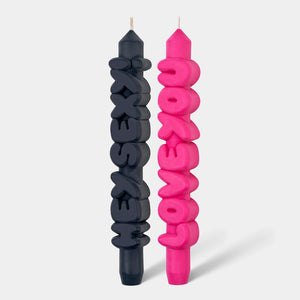 Front view of bold text taper candles reading “Hey Sexy!” in black and “Love You” in pink, handcrafted with a playful design.