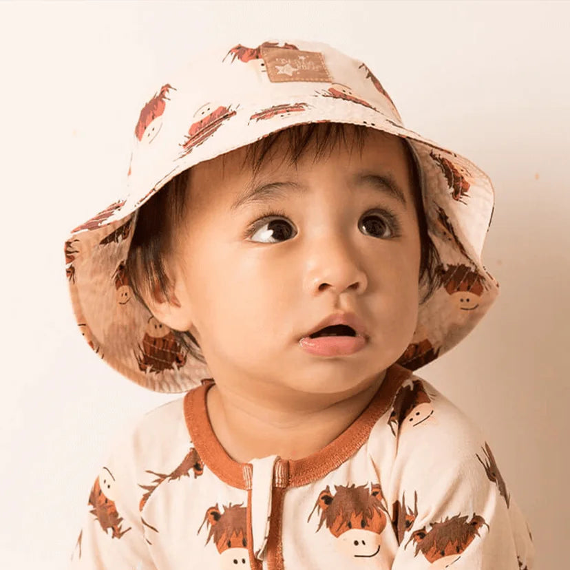 Child wearing cream highland cow bucket hat with matching romper