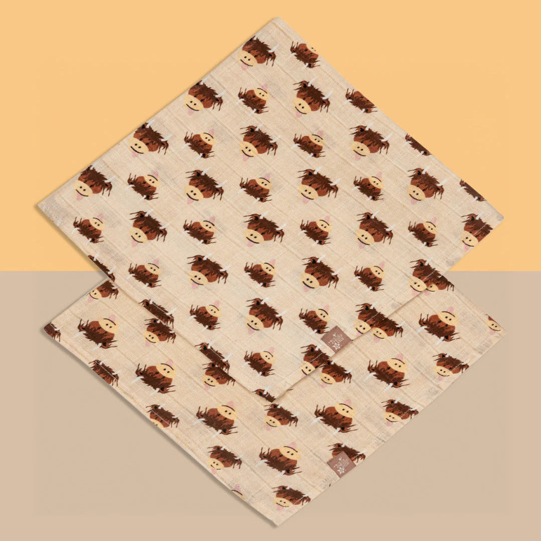 Two highland cow muslin squares flat on split background