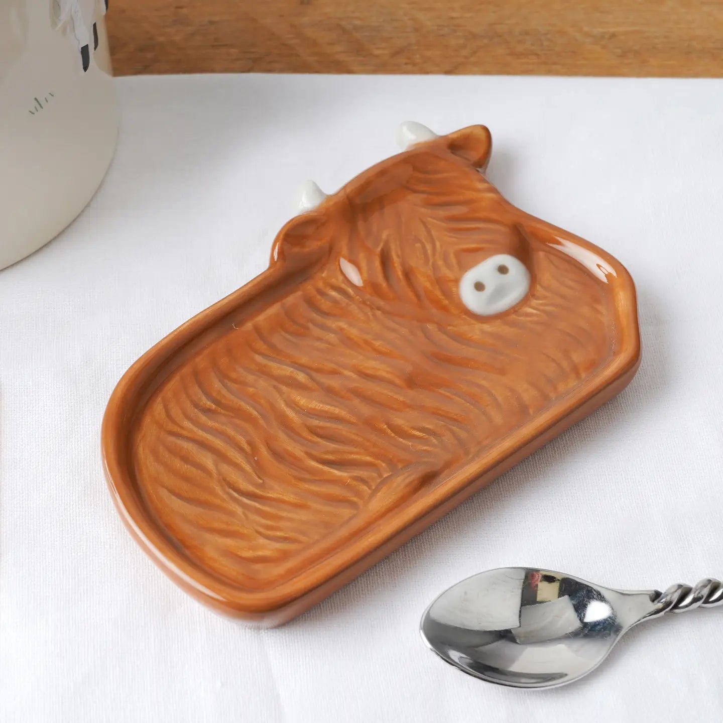 Front view of ceramic Highland Cow tea bag dish with spoon.