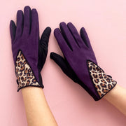 Purple berry suedette gloves with leopard print cuff detail, worn on hands against a pink background.