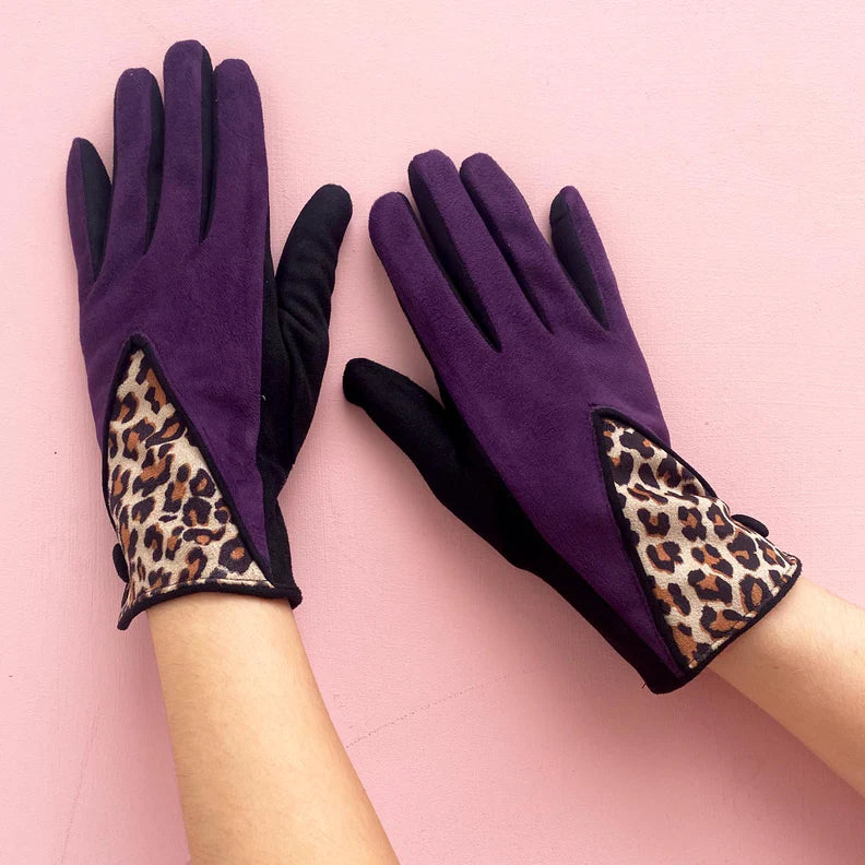 Purple berry suedette gloves with leopard print cuff detail, worn on hands against a pink background.