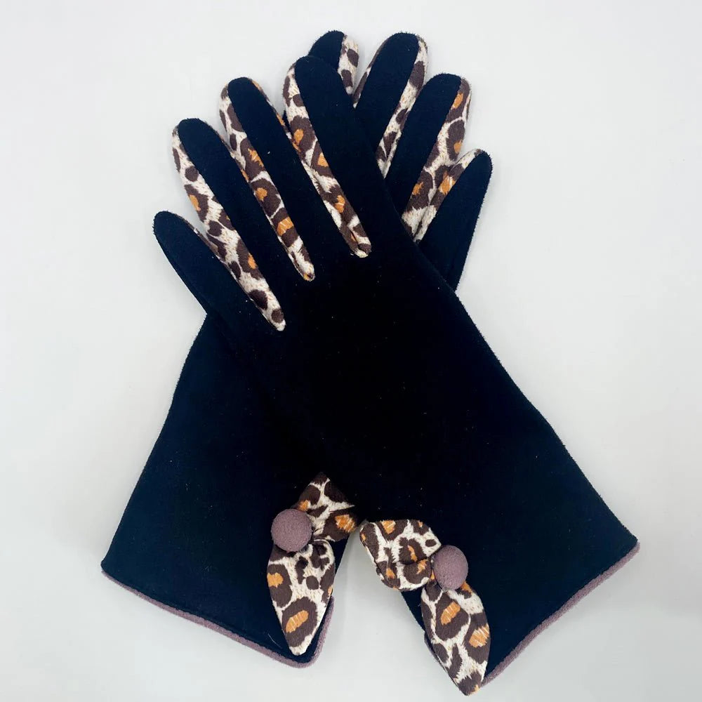 Flat lay of black gloves with leopard print bows crossed neatly on white background.