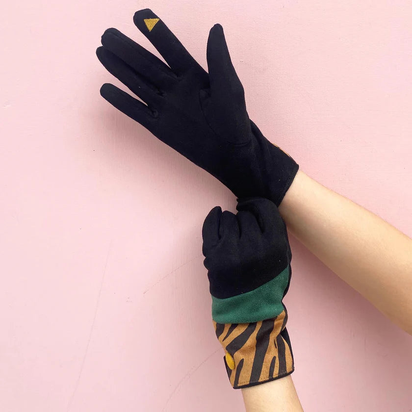 Black suedette gloves with touchscreen fingertip detail and tiger print cuff, styled on hands over a pink background.