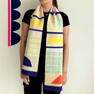 Model wearing the Bloc Abstract Scarf long and loose over a black outfit, showcasing colourful geometric patterns in yellow, mint, coral and navy.