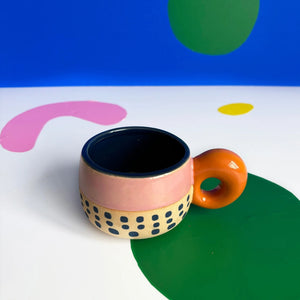 Top-down angle of Bloc Cup with navy interior and hand-painted base on colourful abstract background.