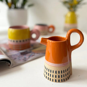 Bloc Jug styled on table with matching Bloc mugs and blurred background.
