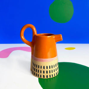 Bloc Jug in bright orange with abstract dot pattern on colourful background.
