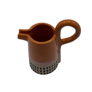 Overhead angled view of orange Bloc Jug with looped handle and pouring spout.