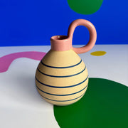 Front view of the House of Disaster Bloc Vase showing bold abstract shapes in pastel and mustard tones on a cream ceramic base, with a narrow cylindrical neck.
