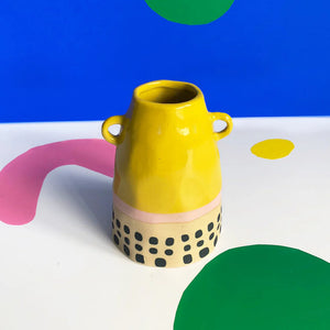 Side angle of yellow ceramic vase with modern block-style design.