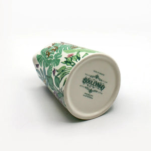 Underside of the Boulevard Cat Jug showing branding stamp, set against lush green foliage print and floral accents.