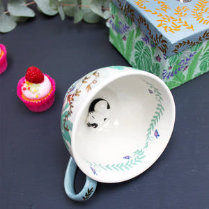 Boulevard Greenhouse cup showing interior 3D sleeping cat with floral and vine detailing.