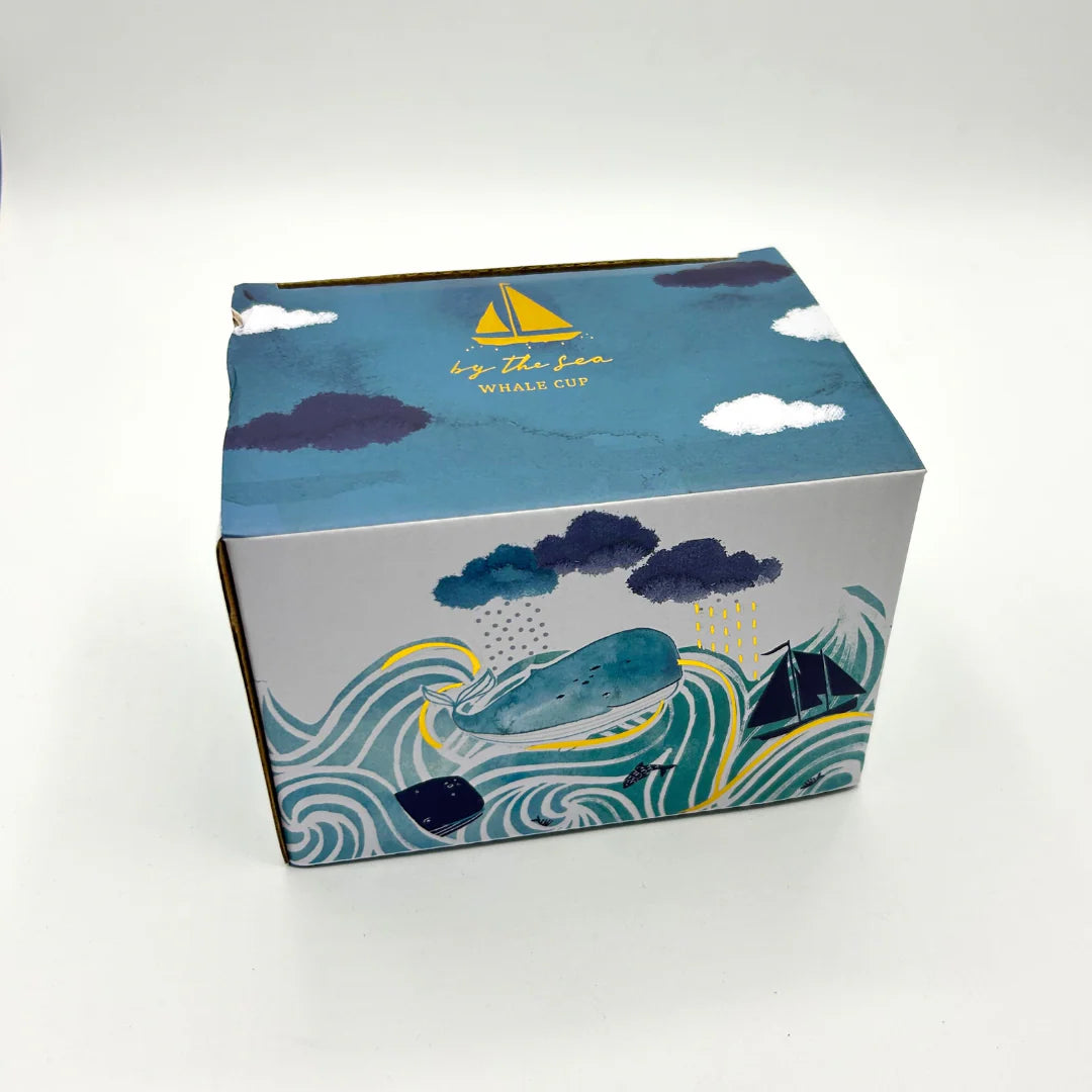 Gift packaging for By The Sea mug featuring illustrated stormy ocean, whales, and sailboats.