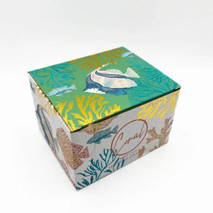 Vibrant illustrated gift box for the Coral Fish Mug featuring colourful underwater artwork with fish, coral, and gold foil accents.