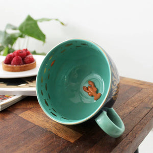 Interior view of Coral Lobster Cup showing teal glaze, scattered goldfish, and a detailed ceramic lobster figurine at the base.