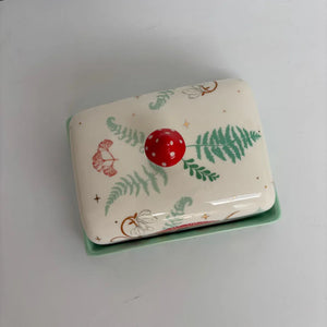 Top-down view of the Forage Butter Dish showing bright red ceramic toadstool handle and full fern pattern on cream lid.