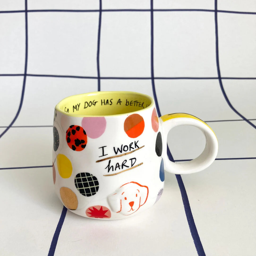 Ceramic mug with colourful polka dots, “I work hard” quote, and 3D dog face detail on a white background.