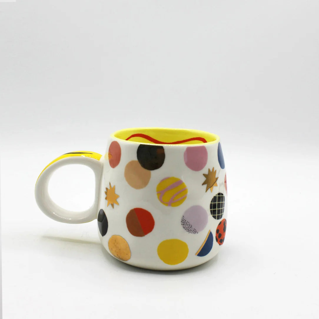 Rear view of decorative ceramic mug covered in multicoloured and metallic polka dots with playful, arty design.