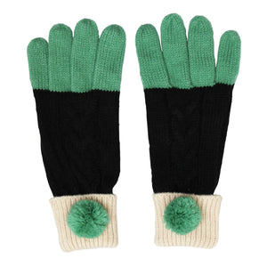 Flat lay of Loop Black Mittens with green fingertips and chunky cable knit black body, finished with cream cuffs and green pom-poms.