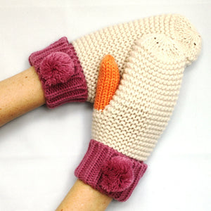 Model wearing Loop Cream Mittens featuring soft cream knit, orange thumbs, and berry cuffs with pom-pom detail
