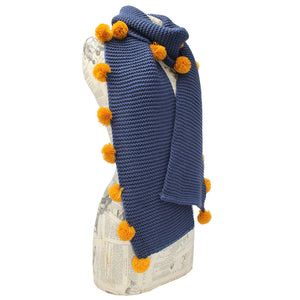 Front view: Navy knitted scarf with mustard pom poms styled on vintage mannequin.