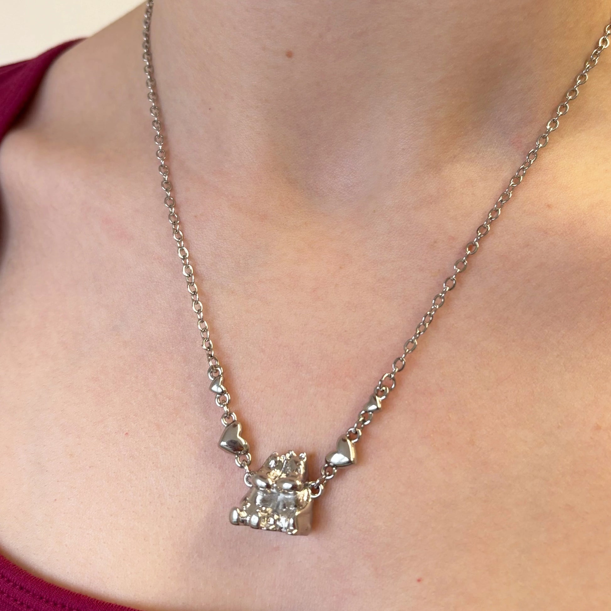 Moomin necklace worn around the neck showing silver chain and hugging Moomin characters.