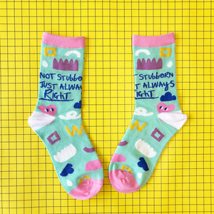 Flat lay of pastel bamboo socks with abstract shapes and “Not stubborn, just always right” slogan on yellow grid background.