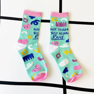 Pair of slogan socks laid flat on a white and black grid background showing full design and fun message.