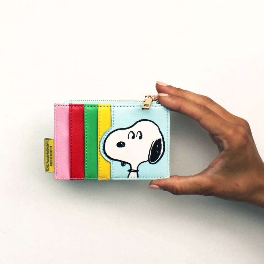 Hand holding back of Peanuts purse showing rainbow card slots and Snoopy portrait.