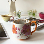 Overhead view of Posy Orange Mug and matching tableware – floral ceramic mug with orange base and detailed botanical illustrations.