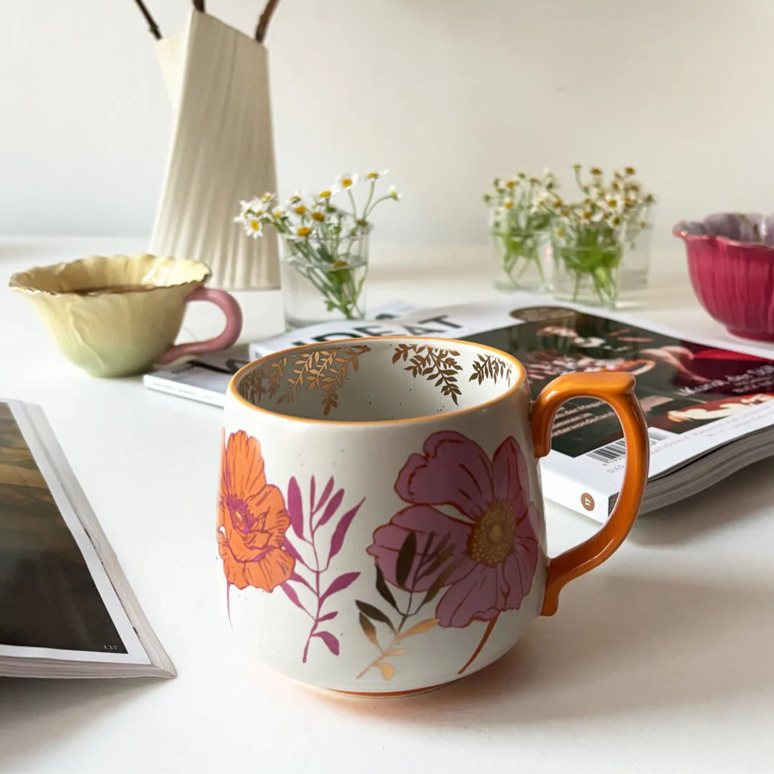 Overhead view of Posy Orange Mug and matching tableware – floral ceramic mug with orange base and detailed botanical illustrations.
