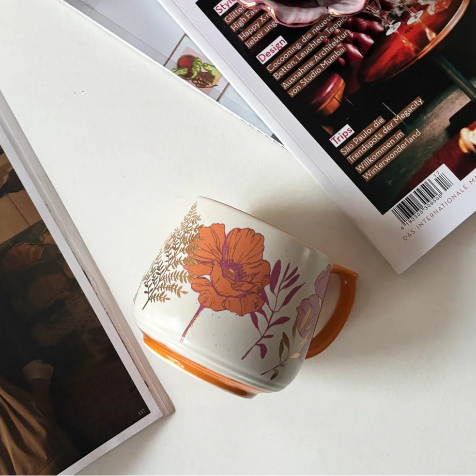 Overhead view of Posy Orange Mug and matching tableware – floral ceramic mug with orange base and detailed botanical illustrations.