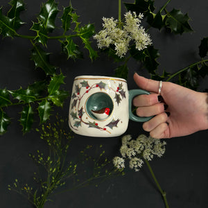 Hand holding the Secret Garden robin cup, showing teal handle and 3D robin nestled inside circular nook.