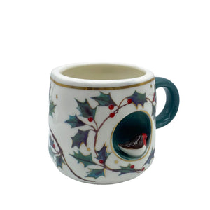 Angled front view of Secret Garden robin cup showing detailed holly pattern, gold accents, and bird feature.