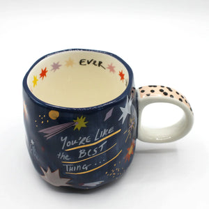 Close-up of House of Disaster mug with star details and handwritten quote, view of inside text “EVER”.
