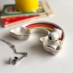 A close-up of the House of Disaster Peanuts Rainbow Trinket Dish on a white surface, featuring a sculpted Snoopy figure sitting on one end and a colourful rainbow design.