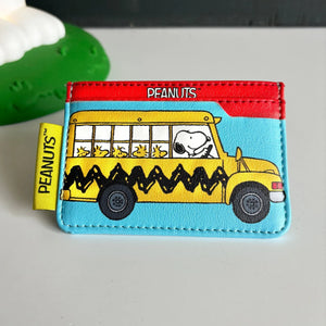 Front view of House of Disaster Peanuts ‘Bus’ Cardholder featuring Snoopy driving a yellow school bus with Woodstock passengers.