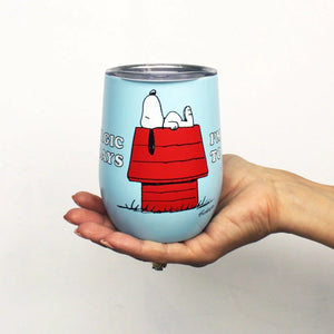 A hand holding the travel mug, providing a sense of scale and highlighting the fun Snoopy design.