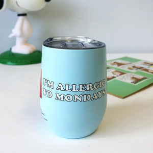 A close-up of a light blue stainless steel travel mug with the phrase “I’m Allergic to Mondays” printed in bold black letters.