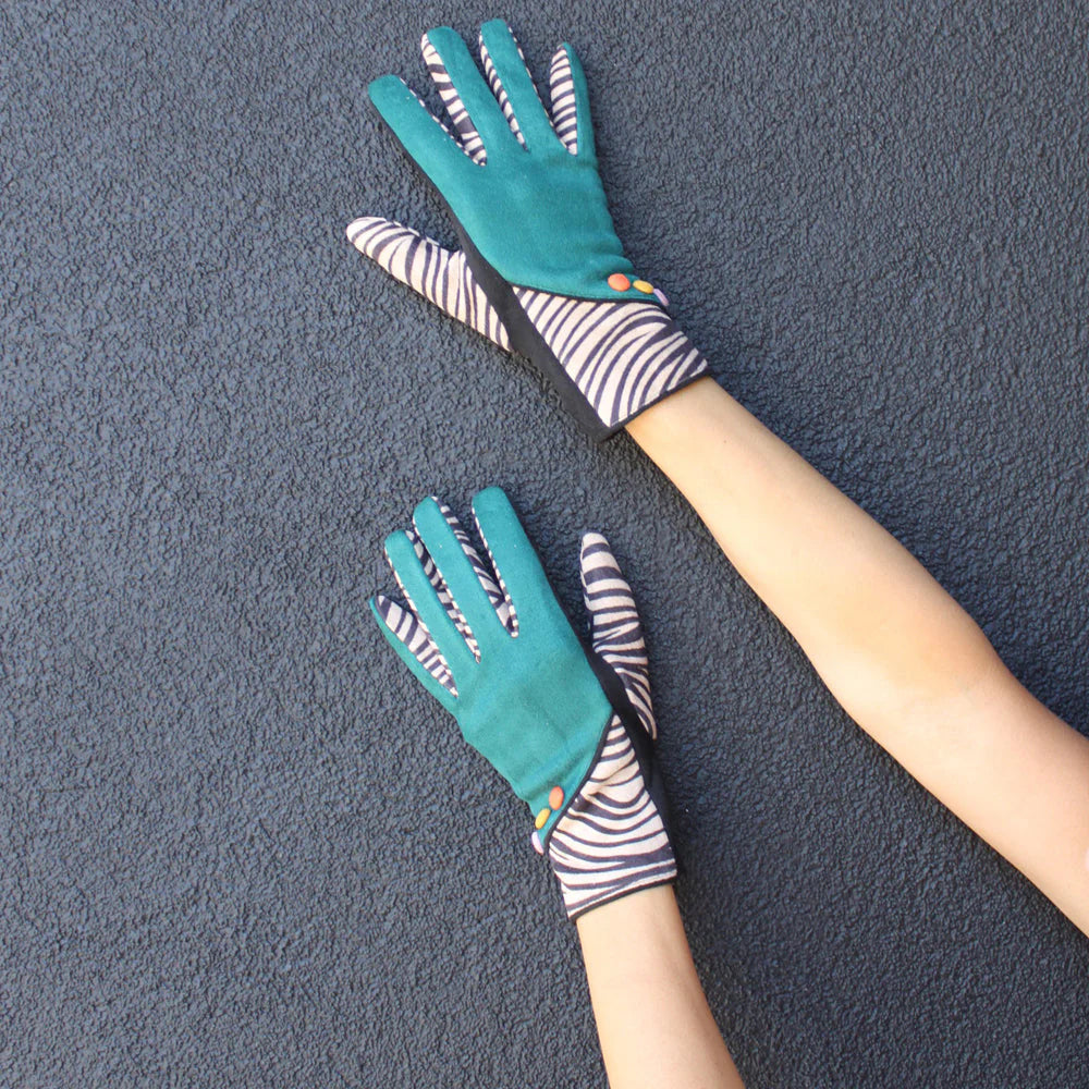 Zebra animal print winter gloves with green panels and striped detail, shown worn on hands against a dark textured wall.