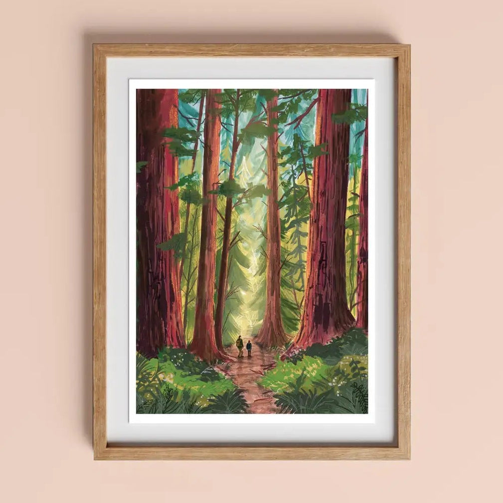 Into the Trees Version 2 art print A4 by Charis Raine Illustration framed on wall, featuring giant redwood trees and woodland path.