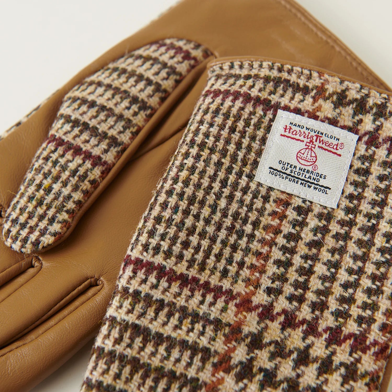 Close-up of Harris Tweed® beige dogtooth gloves showing woven wool pattern and official Harris Tweed® label.
