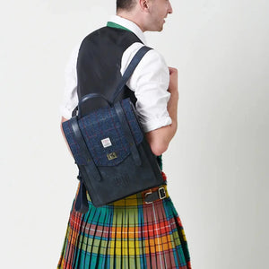 A navy over-check Islander Carloway backpack worn by a man in a kilt.