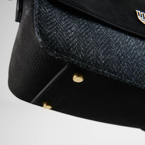 Detailed underside view of Caithness Clutch Bag showing gold protective base studs and the texture of the black herringbone Harris Tweed® overlay.