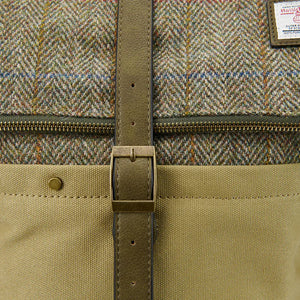 A close-up of the chestnut herringbone Harris tweed fabric on an Islander Harris tweed canvas backpack. A brass buckle is visible on a strap.