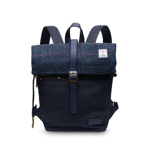 A navy over-check Harris tweed canvas backpack with the shoulder straps visible behind.